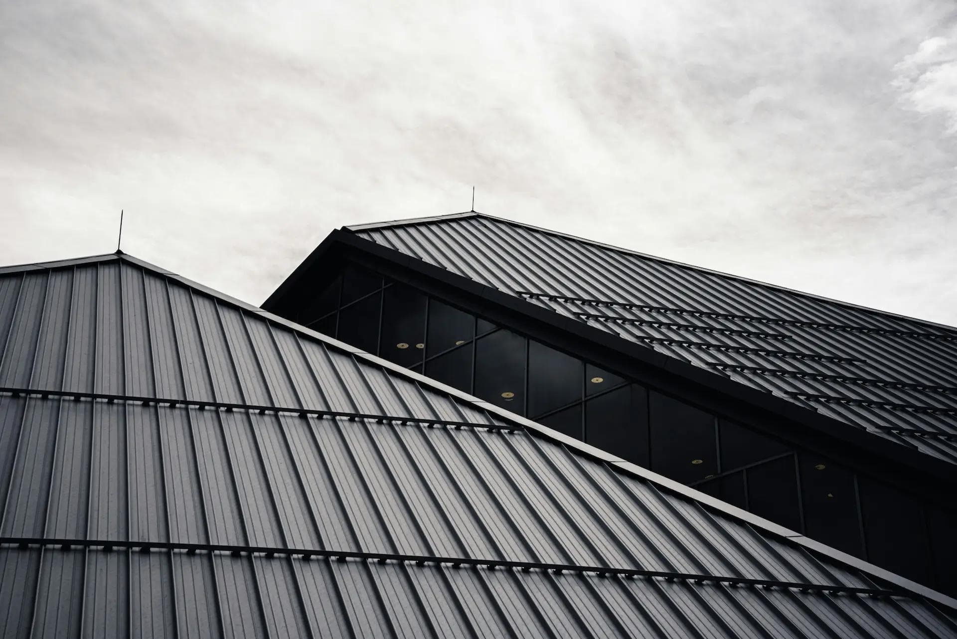 Grey image of a metal roof with a light sky as the backdrop.