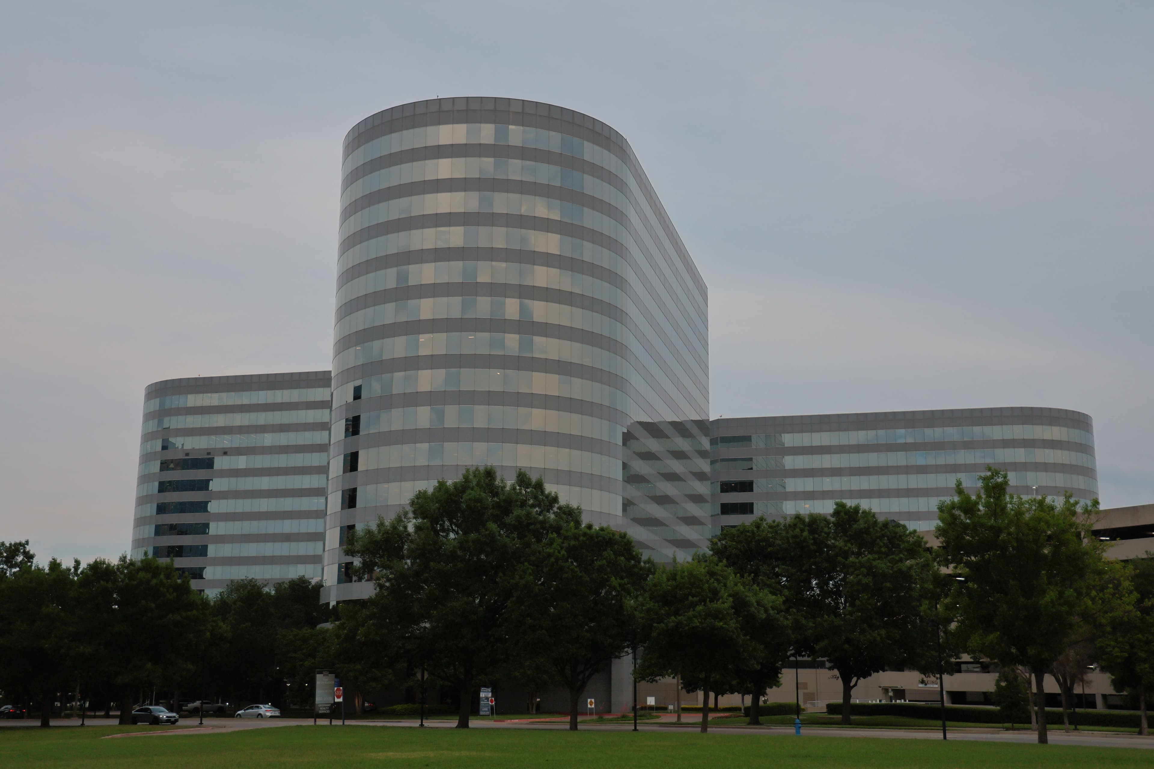 Glass and steel office towers in Richardson, Texas under a partly cloudy sky.
