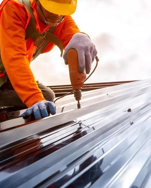 DUBCO worker installing metal roofing panels on a commercial building.